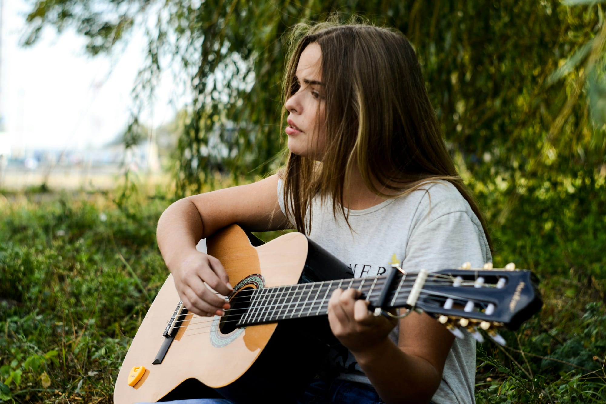 Young woman playing the guitar in the forest