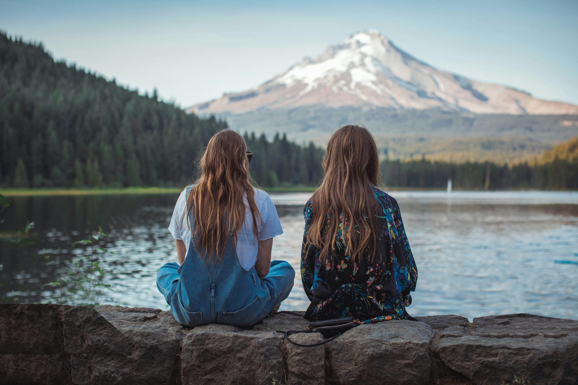 Two sisters sitting next to the water