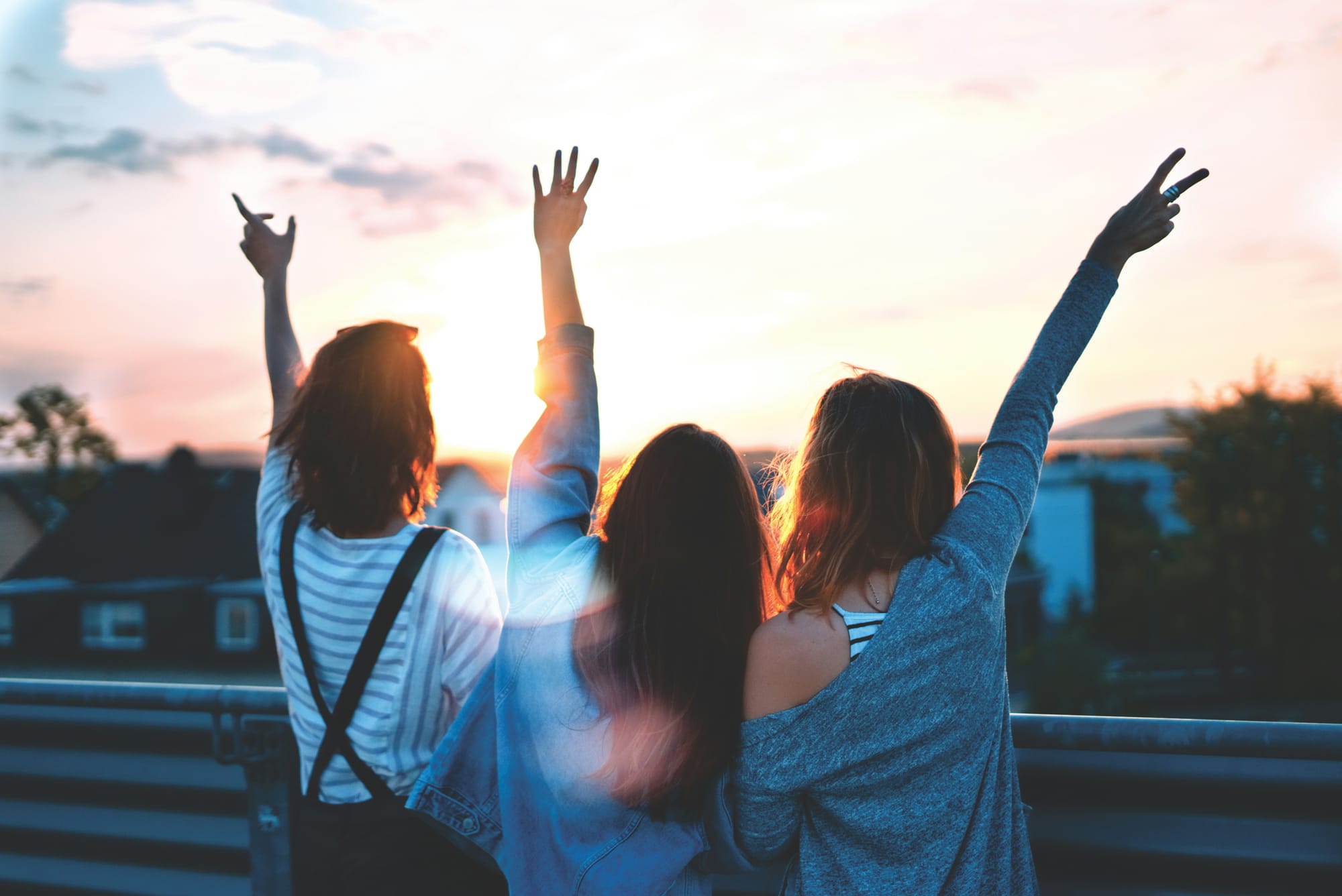 Three girls waving in the sunset